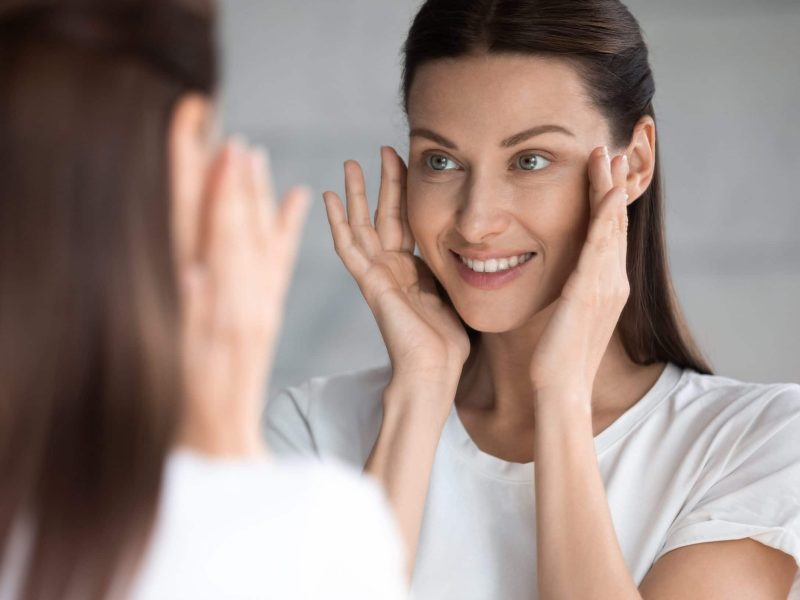 Woman looking at mirror, touching face
